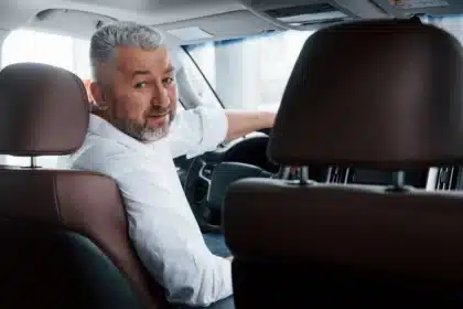 conception of success joyful bearded man in white shirt looks back while sitting in the modern car.jpg